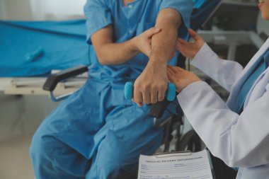 Egzersiz halter tedavi hakkında kol ve omuz sporcu ile erkek hastanın fizik tedavi kavramı veren fizyoterapist adam