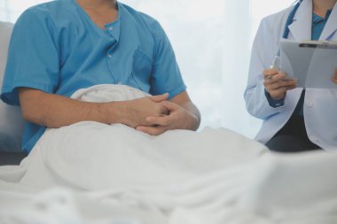 Genç doktor steteskop kullanıyor. Hastanın kalp atışlarını dinle. Kadın bir doktorun erkek bir hastaya muayene yaparken görüntüsü.