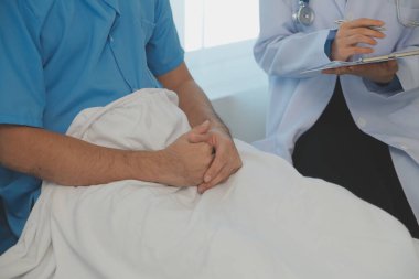 Genç doktor steteskop kullanıyor. Hastanın kalp atışlarını dinle. Kadın bir doktorun erkek bir hastaya muayene yaparken görüntüsü.