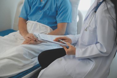 Genç doktor steteskop kullanıyor. Hastanın kalp atışlarını dinle. Kadın bir doktorun erkek bir hastaya muayene yaparken görüntüsü.