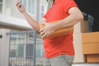 Asya teslimat ekspresi kuryesi genç adam, kadın müşteriye kutu veriyor. Evin önünde koruyucu yüz maskesi takıyor.