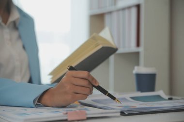 Ofiste dizüstü bilgisayarda oturan yakışıklı Asyalı iş kadını Milli Gelir İdaresi 'nin belgelerini kontrol ederek rapor hazırlıyor..