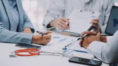 Bir grup doktor ve hasta tıbbi geçmişi tartışıyor.