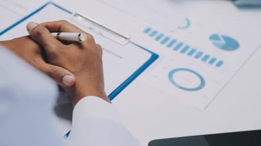 İş adamı elinde kalemle ofis masasındaki grafiğe işaret ediyor..