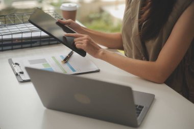 İş yerinde dizüstü bilgisayarında çalışan Asyalı genç bir iş kadınının fotoğrafı..