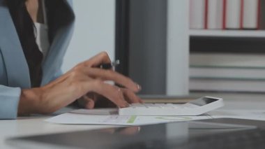 İş kadını büro masasında hesap makinesi kullanıyor.