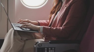 Havaalanı uçağında dizüstü bilgisayar kullanan iş kadını