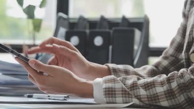 Ofisinde akıllı telefonu olan bir iş kadını.