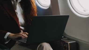 İş kadını uçakta bilgisayarı online uçuş için kullanıyor..