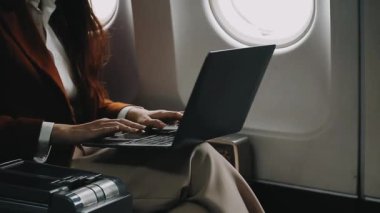 Uçağın camında dizüstü bilgisayar kullanan genç bir kadın.