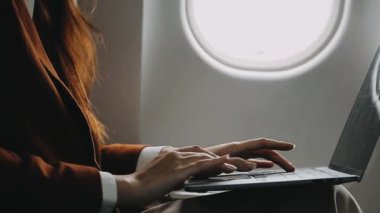 Uçakta dizüstü bilgisayar kullanan kadın.