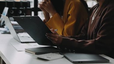 Genç iş kadını ofiste otururken dizüstü bilgisayar kullanıyor. Tablet kullanan işadamları.