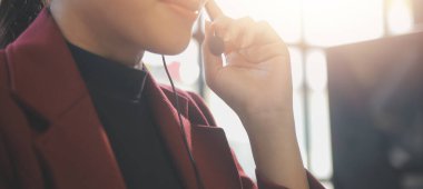 Çağrı merkezinde dost canlısı kadın yardım hattı operatörü. Çağrı merkezinde çalışan ve mikrofonu elleriyle tutan genç bir kadın..