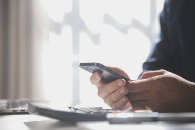 İş adam ellerini meşgul ofis Masası, tahta masada oturan telefon yazarak genç erkek öğrenci, cep telefonu kullanarak iç, arka görünümünde akıllı telefon kullanarak bir adamın elleri yan görünüm görüntüsünü flare