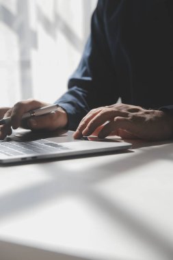 Bir kahve dükkanında dizüstü bilgisayarı üzerinde çalışan genç bir adamın kırpılmış görüntüsü, iş adamının elleri ofis masasında dizüstü bilgisayarla meşgul, genç bir erkek öğrenci ahşap masada oturuyor.