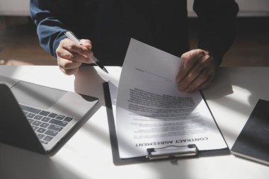 Asyalı işadamı ofis işyerindeki belge raporlarını bilgisayar laptopuyla inceliyor. Hukuk uzmanı, profesyonel avukat mali belgeleri okuyup kontrol ediyor ya da sigorta sözleşmesini.