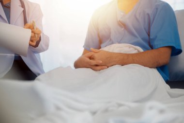 Genç doktor steteskop kullanıyor. Hastanın kalp atışlarını dinle. Kadın bir doktorun erkek bir hastaya muayene yaparken görüntüsü.