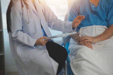 Genç doktor steteskop kullanıyor. Hastanın kalp atışlarını dinle. Kadın bir doktorun erkek bir hastaya muayene yaparken görüntüsü.