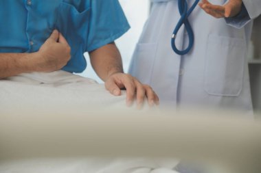 Genç doktor steteskop kullanıyor. Hastanın kalp atışlarını dinle. Kadın bir doktorun erkek bir hastaya muayene yaparken görüntüsü.