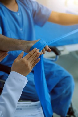 Hastaya direnç bandı takan fizyoterapist.