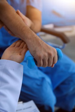 Egzersiz halter tedavi hakkında kol ve omuz sporcu ile erkek hastanın fizik tedavi kavramı veren fizyoterapist adam