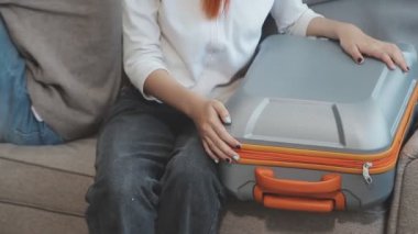 Kanepede oturan ve bavul taşıyan bir kadın.