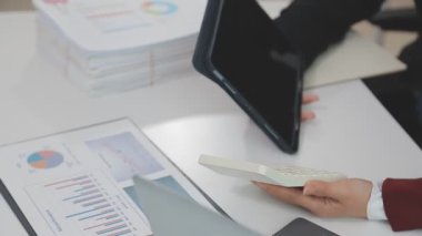 Ekonomik raporlarla çalışan ve modern ofisteki finansal grafikleri analiz eden iş adamları.