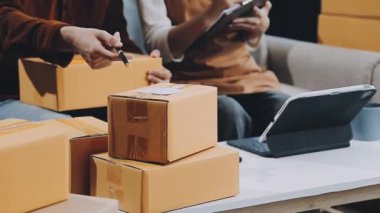 Masada dizüstü bilgisayarı ve paket kutusu olan adam var.