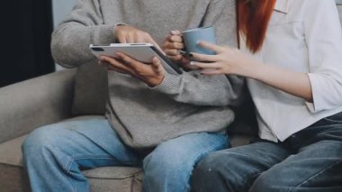 Oturma odasında oturup dijital tablet kullanan iki genç kadın..