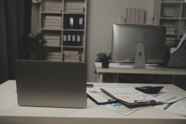 Çalışma odasındaki toplantı masasında kapağı açık dizüstü bilgisayar.