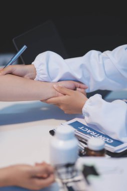 Ofiste çalışan ve hastayı dinleyen doktor semptomlarını, sağlık hizmetlerini ve yardım kavramlarını açıklıyor.