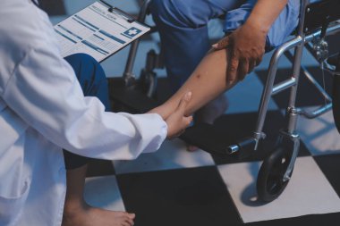 Asyalı, genç, profesyonel, dost canlısı mavi hastane üniformalı kadın hemşire yaşlı, yaşlı, sağlıksız, dört bacaklı, yürüyen bir hastanın fiziksel terapisine yardım ediyor..