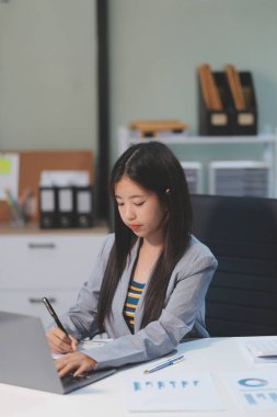 Ofiste dizüstü bilgisayarda çalışan neşeli iş kadını, iş yerinde resmi takım elbiseli Asyalı mutlu iş kadını. Çekici bayan ofis çalışanı gülümsemesi.