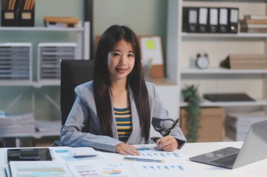 Ofiste dizüstü bilgisayarda çalışan neşeli iş kadını, iş yerinde resmi takım elbiseli Asyalı mutlu iş kadını. Çekici bayan ofis çalışanı gülümsemesi.