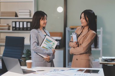 Dijital tablet üzerinde çalışan iki genç kadının fotoğrafı. Yaratıcı kadın yöneticiler ofiste buluşup tablet bilgisayar kullanıyor ve gülümsüyor..