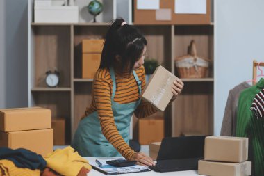 Vlogger, blog yazarı, küçük KOBİ iş kadını güzel bir kadın cep telefonuyla kıyafetleri satıyor canlı yayın satışı yapıyor, ana ofiste ürün sunumu detaylarını gösteriyor, girişimci ekommerce