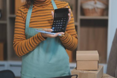 Vlogger, blog yazarı, küçük KOBİ iş kadını güzel bir kadın cep telefonuyla kıyafetleri satıyor canlı yayın satışı yapıyor, ana ofiste ürün sunumu detaylarını gösteriyor, girişimci ekommerce