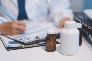 Doktor masasında oturuyor ve hastası için reçete yazıyor.