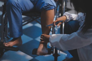 Asyalı, genç, profesyonel, dost canlısı mavi hastane üniformalı kadın hemşire yaşlı, yaşlı, sağlıksız, dört bacaklı, yürüyen bir hastanın fiziksel terapisine yardım ediyor..