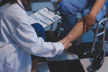 Asyalı, genç, profesyonel, dost canlısı mavi hastane üniformalı kadın hemşire yaşlı, yaşlı, sağlıksız, dört bacaklı, yürüyen bir hastanın fiziksel terapisine yardım ediyor..