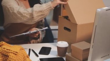 Kadın, müşteriyle birlikte kafede paket tutuyor.