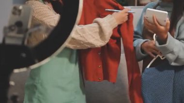 Beyaz elbiseli genç bir kadın ve elinde tablet olan bir şapka.