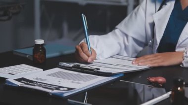 Modern bir klinikte kadın doktor panoya yazı yazıyor.