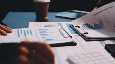 Ofisteki ofis masasında mali tablolar ve hesap makinesiyle çalışan işadamlarının yakın görüntüsü.
