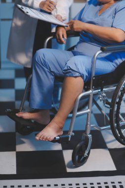 Asyalı, genç, profesyonel, dost canlısı mavi hastane üniformalı kadın hemşire yaşlı, yaşlı, sağlıksız, dört bacaklı, yürüyen bir hastanın fiziksel terapisine yardım ediyor..