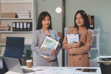 Dijital tablet üzerinde çalışan iki genç kadının fotoğrafı. Yaratıcı kadın yöneticiler ofiste buluşup tablet bilgisayar kullanıyor ve gülümsüyor..