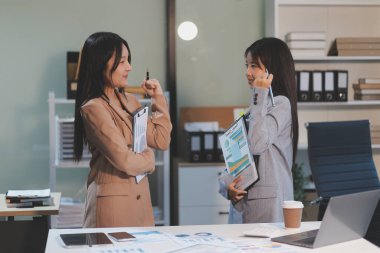 Dijital tablet üzerinde çalışan iki genç kadının fotoğrafı. Yaratıcı kadın yöneticiler ofiste buluşup tablet bilgisayar kullanıyor ve gülümsüyor..