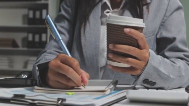 Kadın kahve içerken bilgisayarında çalışıyor.