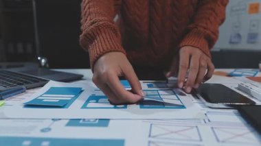 Günlük kıyafet giyen genç tasarımcı, çalışma masasında otururken dijital tablet kullanıyor.