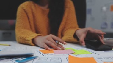 Genç bayan tasarımcı ofiste not kağıdına yazıyor.